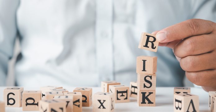 Hand hold wooden block with the word "RISK". Concept risk